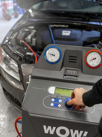 Klimaservice på bil utføres med diagnoseapparat koblet til motorrommet.